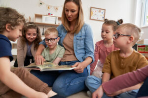 Une éducatrice fait la lecture à un groupe de jeunes enfants.